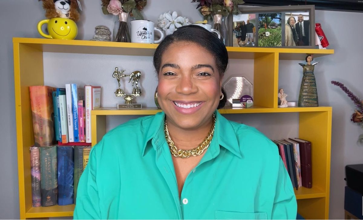 Jas smiling in front of her bookshelf